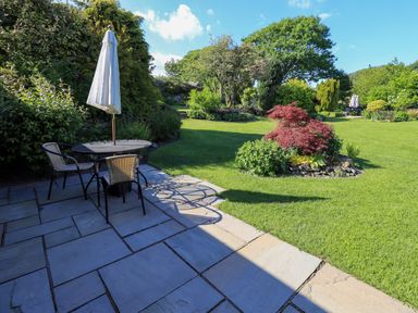 A garden with a table and chairs under an umbrella at The Garden Suite at Fiddler Hall Barn, Newby Bridge