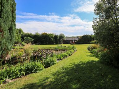 A garden with a pond and bridge at The Garden Suite at Fiddler Hall Barn, Newby Bridge