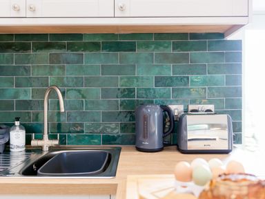 A kitchen countertop with a sink soap dispenser electric kettle and toaster with green tiled backsplash at The Reading Room in Seworgan near Constantine