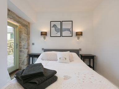 A bedroom with a bed towels on it two bedside tables and framed dachshund pictures on the wall at The Reading Room in Seworgan near Constantine