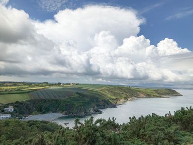 A coastal landscape with cliffs green fields and cloudy sky at The Reading Room in Seworgan near Constantine