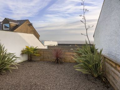 A small outdoor garden area with gravel and various plants surrounded by wooden and white walls at White Stones in Goadsbarrow near Roose