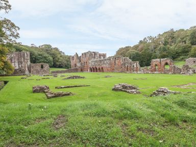 Ruins of a historic stone building surrounded by green grass and trees at White Stones in Goadsbarrow near Roose