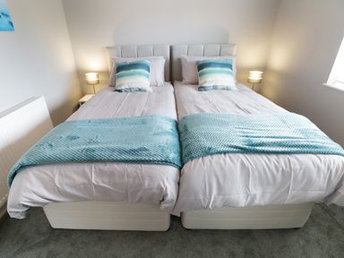 A bedroom with two single beds pushed together with blue blankets and pillows at White Stones in Goadsbarrow near Roose
