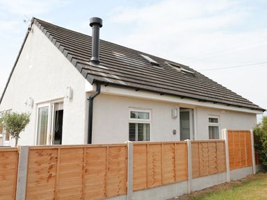 A detached house with a tiled roof and wooden fence surrounding the garden at White Stones in Goadsbarrow near Roose