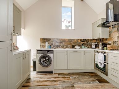 A kitchen with a washing machine oven kettle toaster and cabinets at Foxglove in Goathland