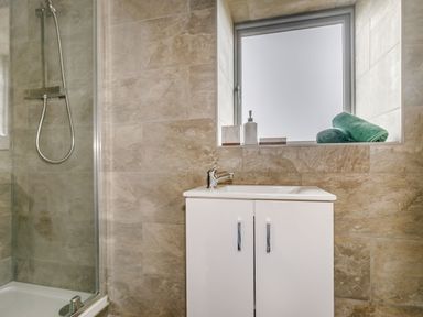 A bathroom with a shower enclosure sink cabinet window with toiletries and rolled towels at Foxglove in Goathland