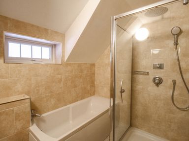 A bathroom with a bathtub and a glass-enclosed shower at Cajun Cottage in West Lulworth