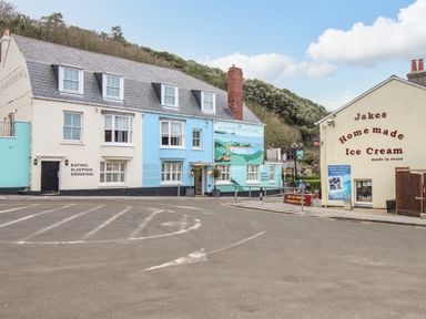A street view with a large building named Lulworth Cove Inn and a small building advertising homemade ice cream in West Lulworth