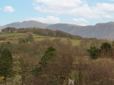 A landscape with trees fields and mountains under a blue sky at Eildon Lodge in Gosforth