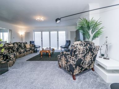 A living room with patterned sofas armchairs a wooden coffee table indoor plant and sculptures at Eildon Lodge in Gosforth