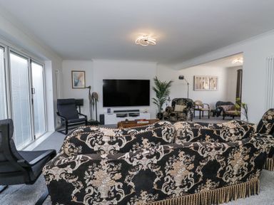 A living room with patterned sofas a large tv and glass doors at Eildon Lodge in Gosforth