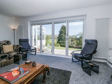 A living room with two armchairs a patterned sofa and a wooden coffee table with a book at Eildon Lodge in Gosforth