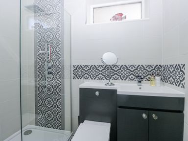 A bathroom with a walk-in shower and a sink with black cabinets at Eildon Lodge in Gosforth