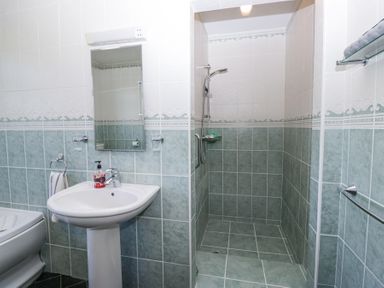 A bathroom with a sink mirror and soap dispenser a walk in shower and a towel rail at Eildon Lodge in Gosforth