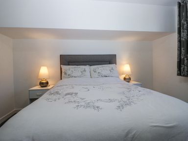 A bedroom with a double bed two bedside tables with lamps and patterned curtains at Eildon Lodge in Gosforth