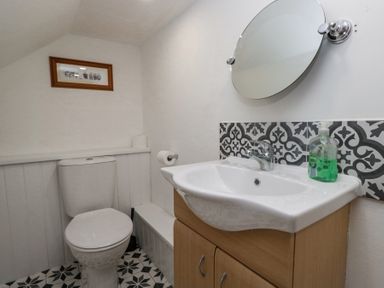 A bathroom with a toilet and a sink with a round mirror above at Eildon Lodge in Gosforth