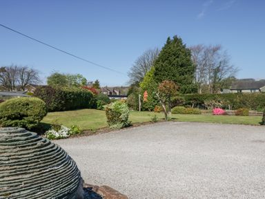 A garden with trimmed bushes and trees beside a gravel driveway at Eildon Lodge in Gosforth