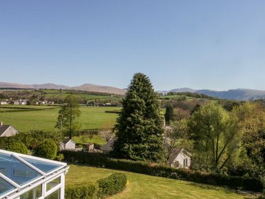A garden with trees and bushes overlooking fields and hills at Eildon Lodge in Gosforth