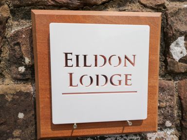 A sign displaying Eildon Lodge on a stone wall in Gosforth