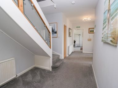 A hallway with a staircase and wall art at Eildon Lodge in Gosforth