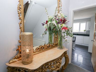 A hallway with a mirror and flower arrangement at Eildon Lodge in Gosforth