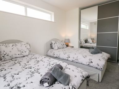 A bedroom with two beds and a wardrobe at Eildon Lodge in Gosforth