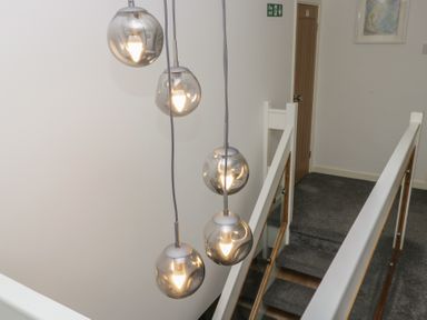 A hallway with hanging light fixtures and a staircase at Eildon Lodge in Gosforth