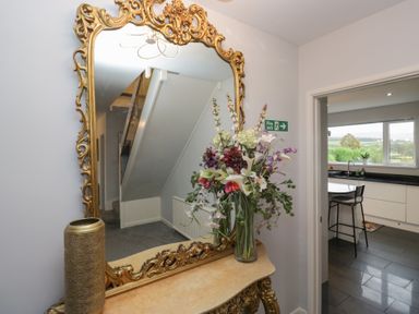 A hallway with a mirror and flowers at Eildon Lodge in Gosforth