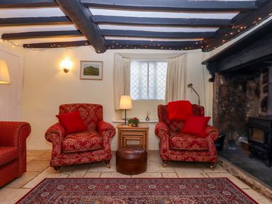 A living room with armchairs and a coffee table at Fox Hat Cottage in Chagford
