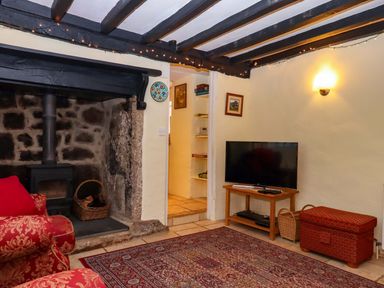 A living room with a fireplace and television at Fox Hat Cottage in Chagford
