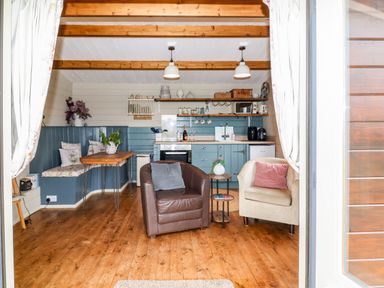 A small kitchen and sitting area with two armchairs a wooden table and shelves at Westfield Lodge in Terrington near Sheriff Hutton