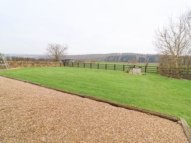 A garden with green grass and a gravel path near wooden fences and trees at Westfield Lodge in Terrington near Sheriff Hutton