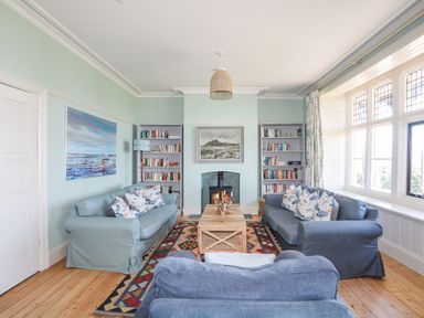 A living room with sofas and bookshelves around a fireplace at Bryn Henllan in Criccieth