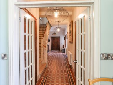 A hallway with tiled floor stairs and hanging light fixtures at Bryn Henllan in Criccieth