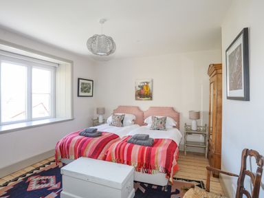 A bedroom with twin beds covered with red striped blankets and gray towels on top at Bryn Henllan in Criccieth