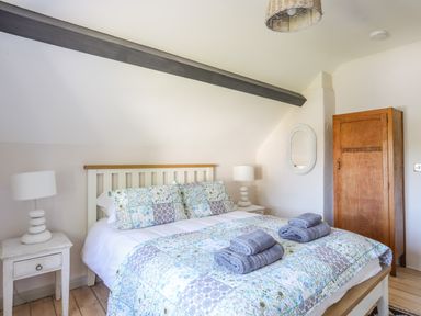 A bedroom with a double bed and floral bedding towels folded on bed with bedside tables and lamps at Bryn Henllan in Criccieth