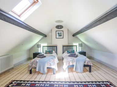 A bedroom with two single beds under a sloped ceiling at Bryn Henllan in Criccieth