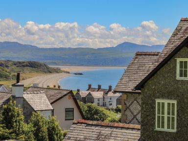 A coastal village with houses near a sandy beach and hills in the background at Bryn Henllan in Criccieth