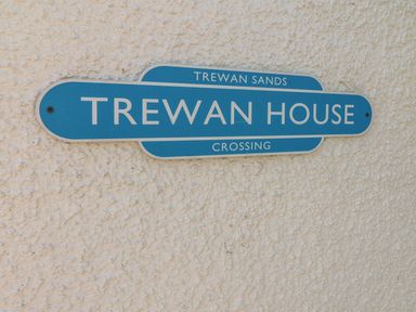 A blue street sign reading Trewan House on a textured white wall at Trewan House in Bryngwran near Rhosneigr Rhosneigr