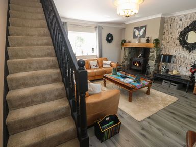 A living room with a staircase a leather sofa a wooden coffee table and a fireplace at Trewan House Bryngwran near Rhosneigr Rhosneigr
