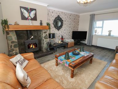 A living room with leather sofas a stone fireplace coffee table and a television at Trewan House Bryngwran near Rhosneigr Rhosneigr