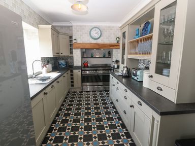 A kitchen with patterned floor tiles and white cabinetry at Trewan House in Bryngwran near Rhosneigr Rhosneigr