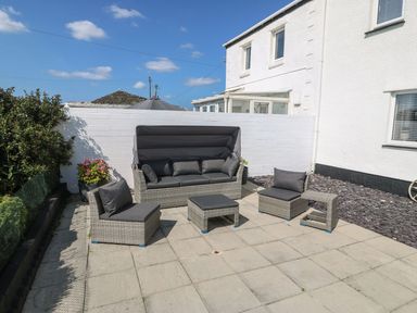 An outdoor patio with garden furniture including a sofa two chairs a table and a footstool at Trewan House in Bryngwran near Rhosneigr Rhosneigr