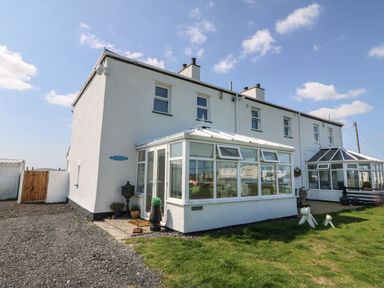 Exterior of a white building with glass conservatories on a lawn at Trewan House Bryngwran near Rhosneigr Rhosneigr