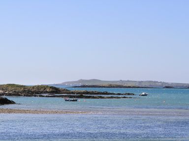 A coastal scene with rocky islands and boats on the water at Trewan Lodge in Bryngwran near Rhosneigr