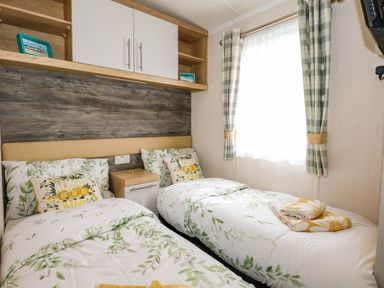 A bedroom with two single beds and floral bedding at Trewan Lodge in Bryngwran near Rhosneigr