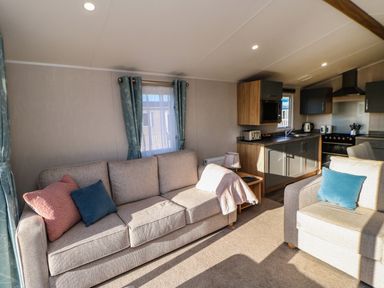 A living room with two sofas and a kitchen area with cabinets and appliances at Wansbeck View 2 in Ashington