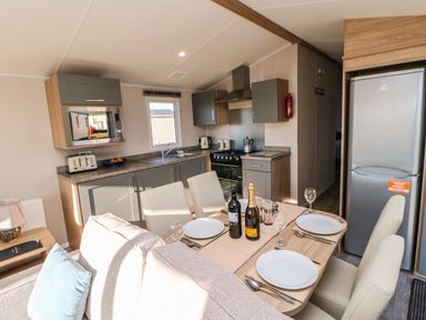 A kitchen and dining area with a table set with plates and glasses a refrigerator and microwave Wansbeck View 2 Ashington