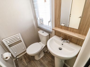 A small bathroom with a toilet sink mirror towel radiator and window blinds at Wansbeck View 2 in Ashington